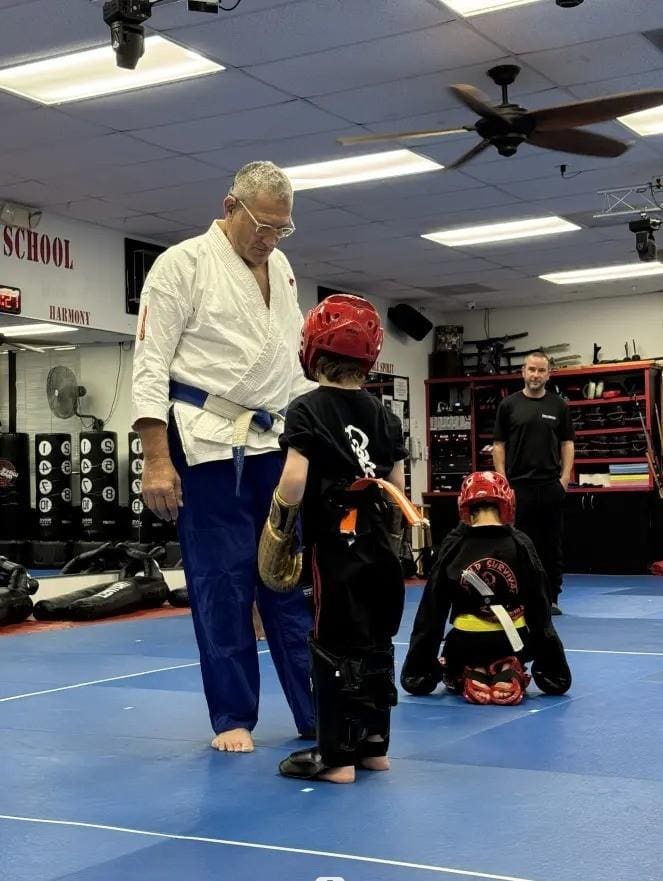 Coach assisting young student with protective gear during jiu jitsu training session