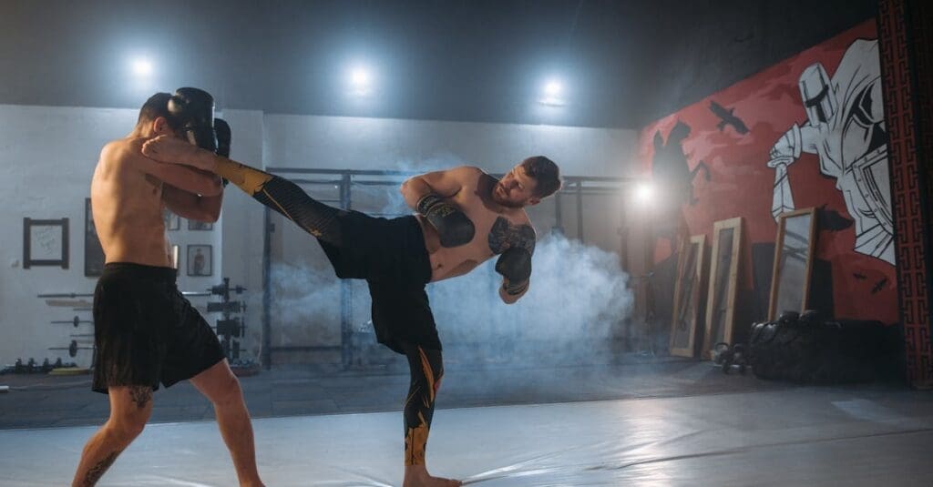 A kickboxer executes a high head kick during a sparring session in a gym, highlighting techniques found in a beginner kick boxing guide.