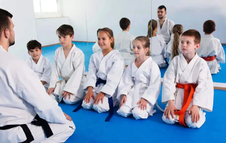 Children listening to an instructor during class, showing beginner martial arts guide