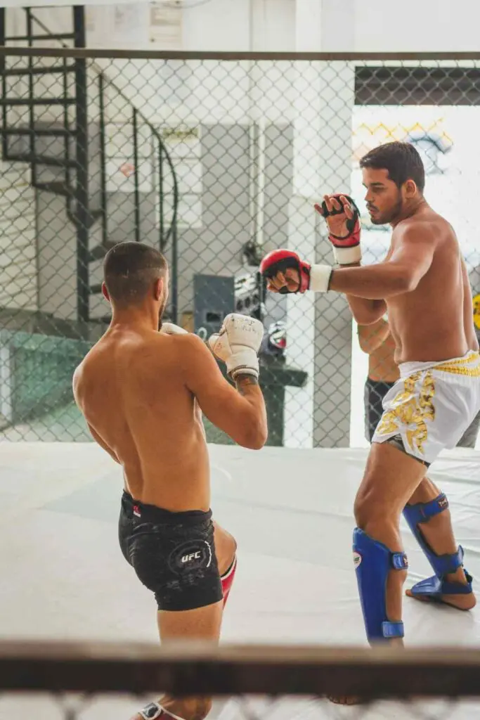 Two fighters sparring and exchanging strikes inside an MMA cage MMA beginner fundamentals