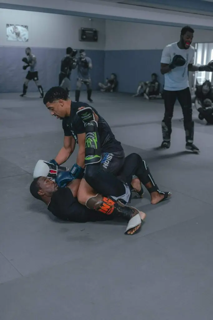 Two martial artists grappling and practicing guard control on the gym mat MMA beginner fundamentals
